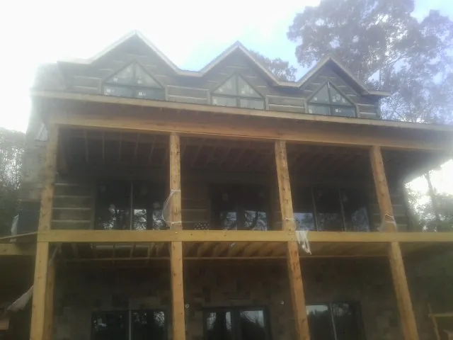 Dormers and porch framing on a large log home under construction — Roof Coating work by our crew in Clover