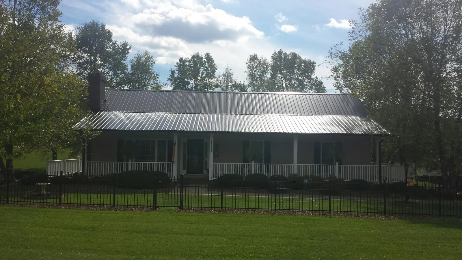 Gray metal roof on a brick ranch with a full width front porch — Gutter Guard Installation work by our crew in Clover