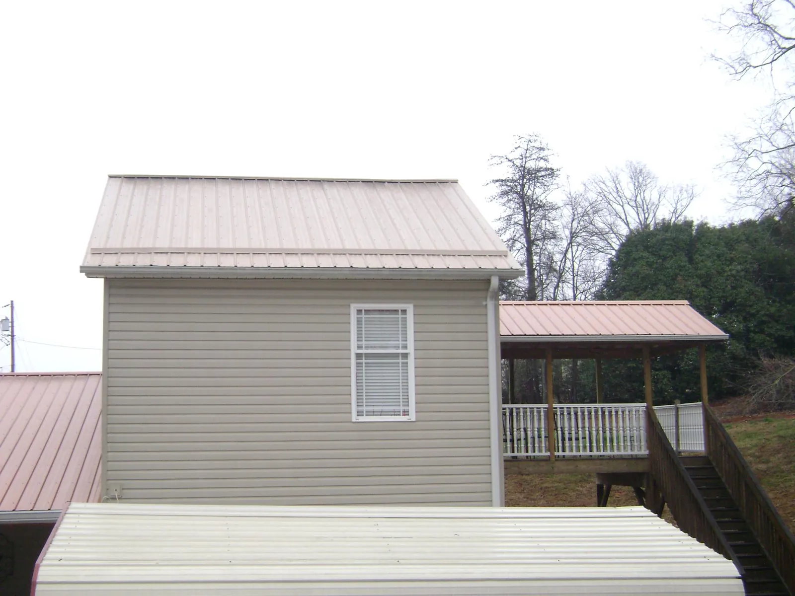 Tan metal roofs on a two story addition and attached porch, from a Roof Replacement job in Clover