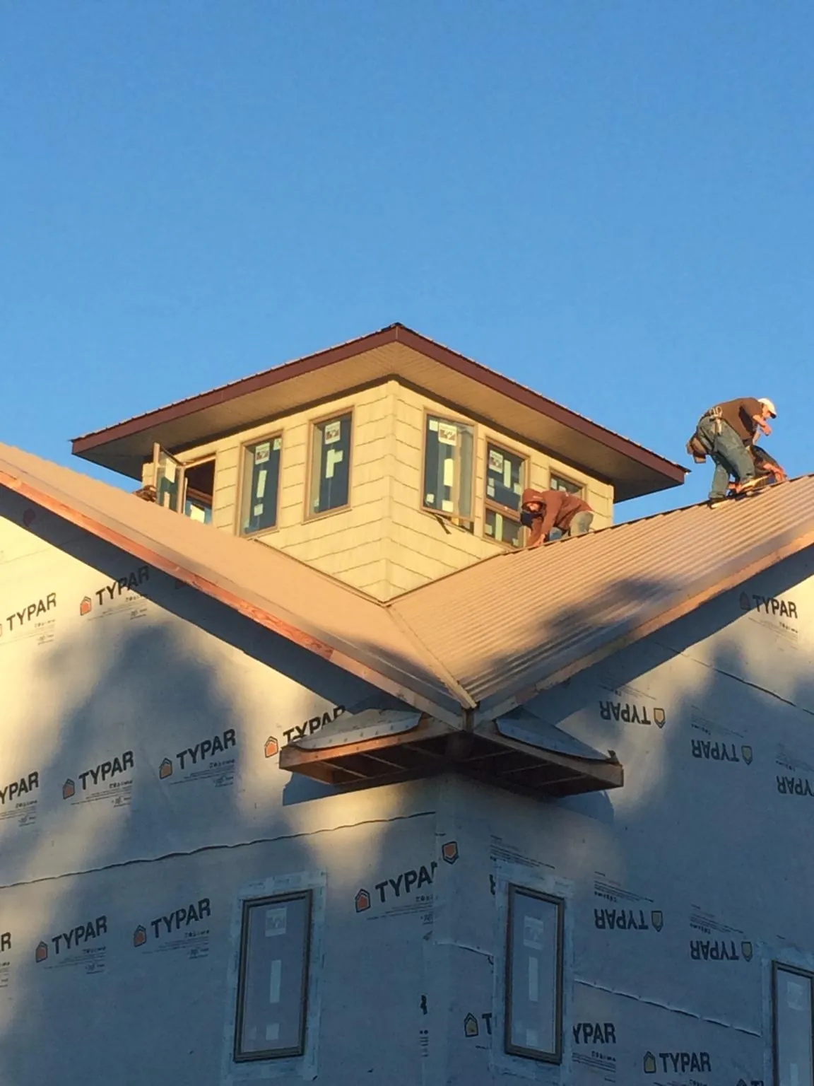 Roofers working around a rooftop cupola on a new metal roof at sunset — Roof Waterproofing in Clover by Roofing Brothers